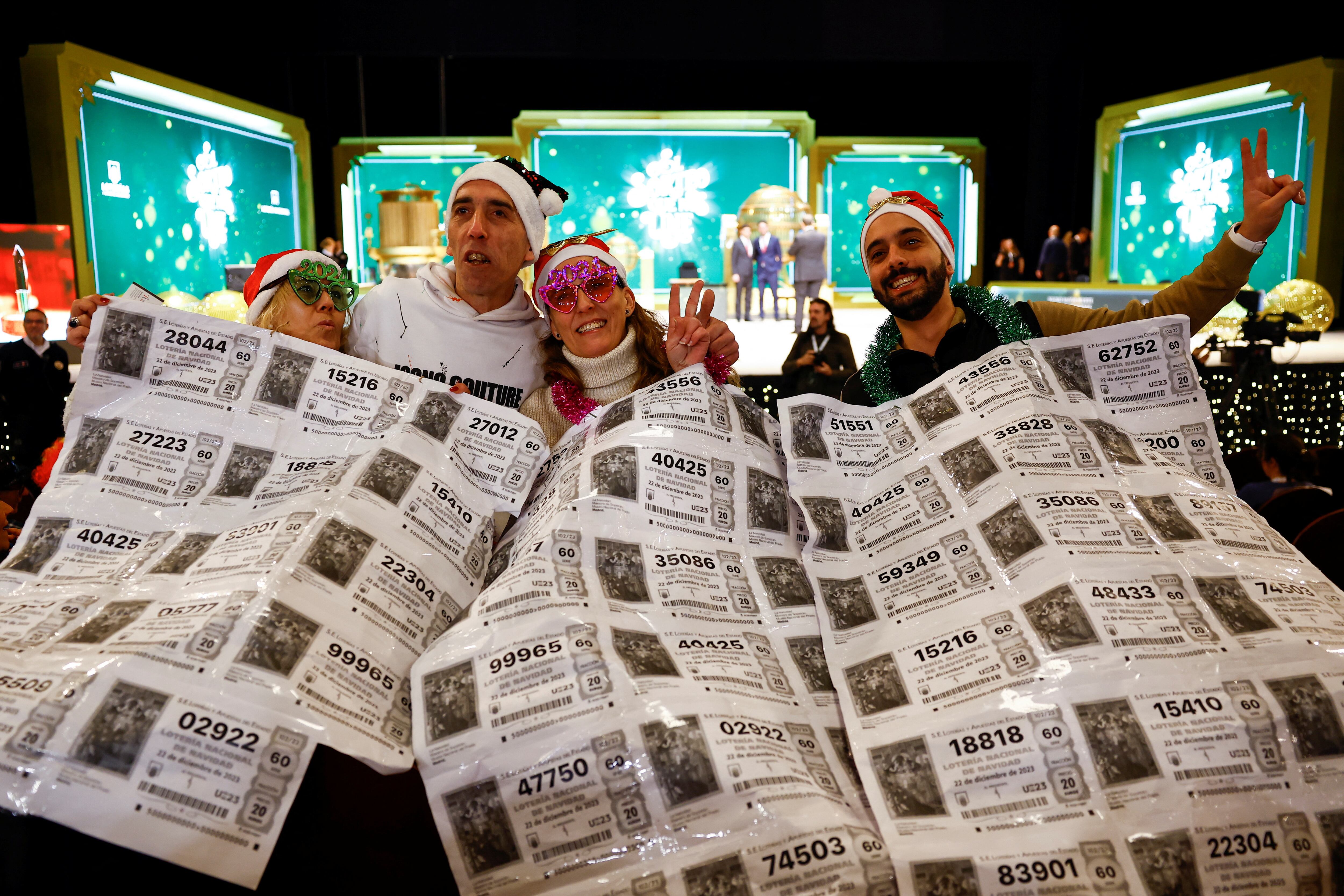 Varios asistentes al sorteo muestran billetes de lotería en el Teatro Real.