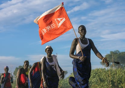 Una mujer de la tribu mundari pasea con una bandera con letras chinas que halló las obras de una carretera en Terekeka (Sudán del Sur) en 2019.