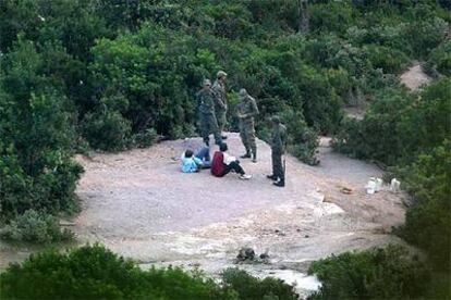 Cuatro soldados marroquíes interrogan a dos subsaharianos en los bosques de Bel Younech, a un kilómetro de Ceuta.