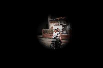 Vistas a través de un agujero de bala, dos mujeres viajan en motocicleta.