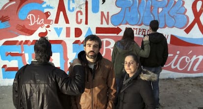 Un grupo de voluntarios de la asociaci&oacute;n Apoyo Positivo frente a un grafiti de concienciaci&oacute;n sobre el sida en el centro de Madrid.