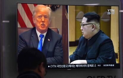 Un hombre mira a Trump y Kim por televisión. 