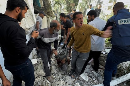 Varios hombres trasladan una víctima de las ataques israelíes a una escuela que alberga a desplazados, este domingo en Gaza.    