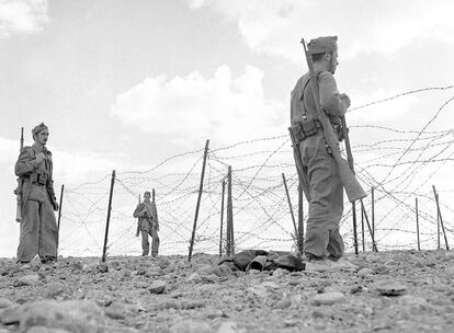 Soldados españoles de infantería patrullan frente a la valla defensiva de una ciudad del Sáhara, probablemente El Aaiún, en los años 1957-1958.