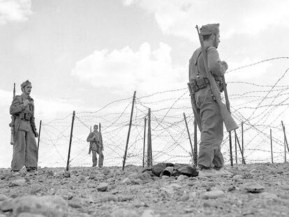 Soldados españoles de infantería patrullan frente a la valla defensiva de una ciudad del Sáhara, probablemente El Aaiún, en los años 1957-1958.