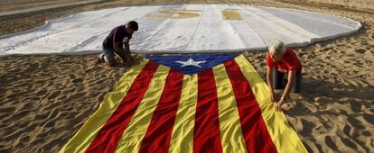 Dos personas extienden una bandera independentista en la playa de El Masnou, cerca de Barcelona.