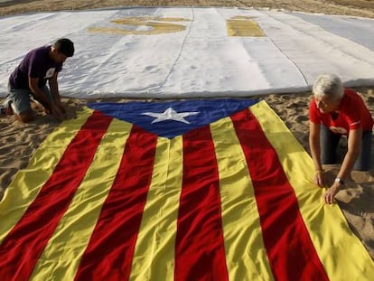 Dos personas extienden una bandera independentista en la playa de El Masnou, cerca de Barcelona.