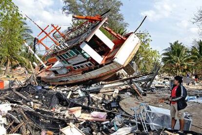Nataya Pumsi, de 36 años, contempla los restos de su casa, reducida a escombros, y de un barco arrastrado por el <i>tsunami</i>, en Ban Nam Khem (Tailandia)

.