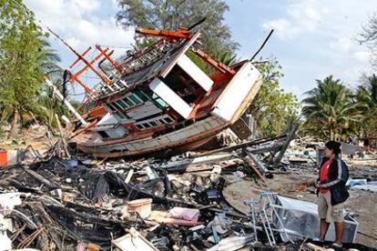 Nataya Pumsi, de 36 años, contempla los restos de su casa, reducida a escombros, y de un barco arrastrado por el <i>tsunami</i>, en Ban Nam Khem (Tailandia)
.