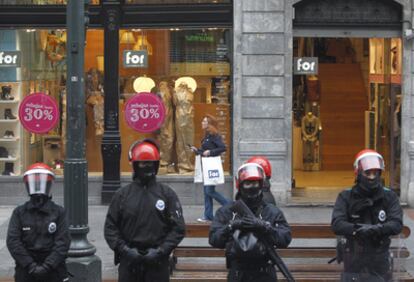 Ertzainas vigilan a los agitadores mientras una clienta sale de la tienda.