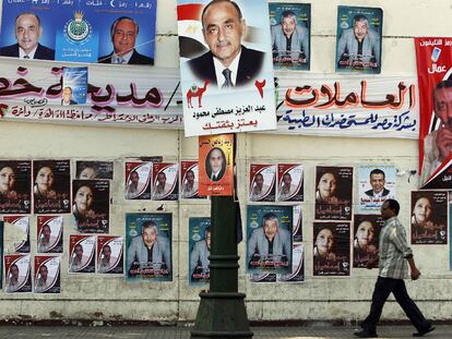 Un hombre camina por una calle de El Cairo repleta de carteles electorales.