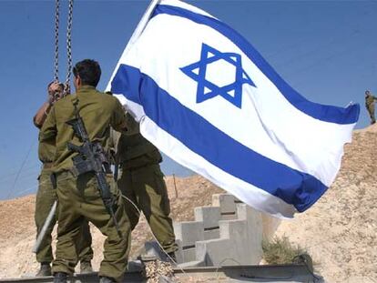 Tres soldados retiran una bandera israelí ayer en una de las entradas de la ciudad de Jericó.