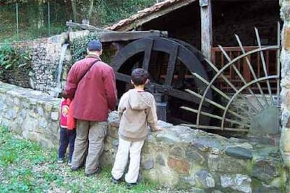 Unos visitantes observan la gran rueda de cangilones en el ecomuseo de la sal.