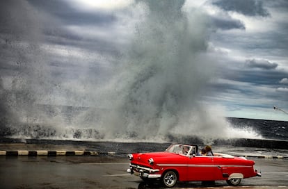 Un descapotable estadounidense de los años cincuenta en el paseo del Malecón de La Habana, con el agua saltando sobre el rompeolas. 