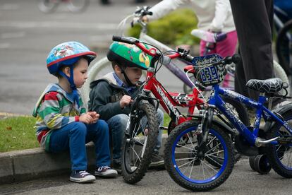 Dos niños se sientan en la acera junto a sus bicicletas,