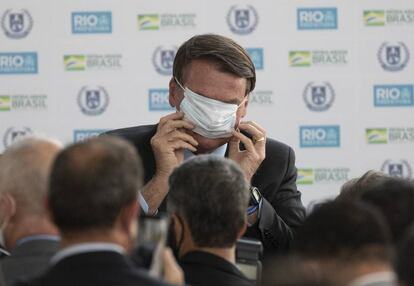 El presidente de Brasil, Jair Bolsonaro, intenta colocarse la mascarilla durante la inauguración de la nueva escuela cívico-militar General Abreu en Río de Janeiro.