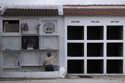 Una mujer limpia una tumba en el cementerio de la localidad sevillana de Huévar del Aljarafe, este lunes.