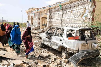 Un grupo de mujeres caminan junto a una casa destruida y los restos de un automóvil después de una explosión provocada por militantes de Al-Shabaab durante un ataque a una estación de policía en las afueras de Mogadishu (Somalia).