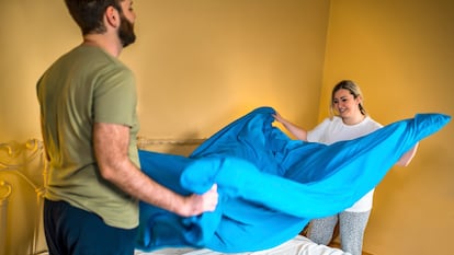 Young happy couple in love making the bed together