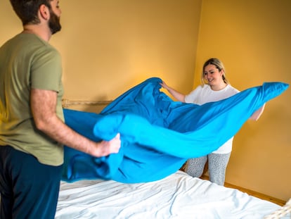 Young happy couple in love making the bed together