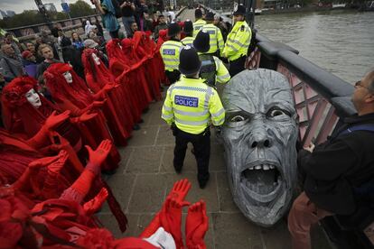 Miembros del colectivo Extinction Rebelion se reúnen alrededor de la cabeza de una estatua confiscada por la policía en el puente Lambeth, en el centro de Londres el lunes 7 de octubre de 2019.