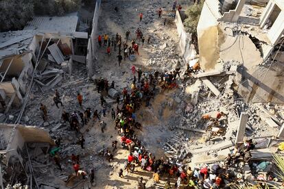 Un grupo de palestinos miran, mientras continúan las labores de búsqueda de supervivientes entre los escombros de un edificio bombardeado por Israel, este sábado en Jan Yunis. 