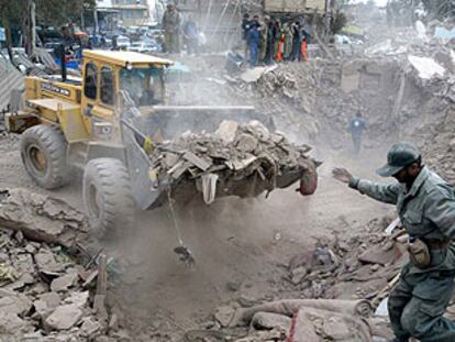 Un hombre guía a una excavadora que retira escombros de una de las viviendas destruidas por el terremoto en la ciudad de Bam.