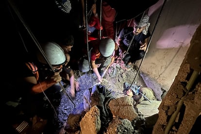 Palestinos intentan rescatar a una mujer atrapada bajo los escombros resultantes de un ataque israelí en Nuseirat, este miércoles. 