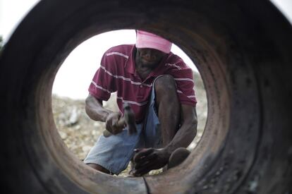 Sony Lonrisme desguaza los restos de un antiguo barril de petróleo en una aldea de artesanos de Croix-des-Bouquets, en las afueras de Puerto Príncipe (Haití). La imagen es del 13 de febrero.