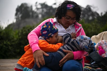 A woman breastfeeds her two children during a breastfeeding festival to tackle social stigma.