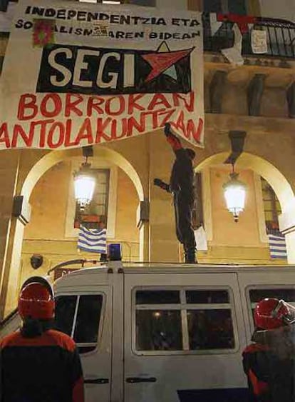 Agentes de la Ertzaintza retiran una pancarta de Segi en San Sebastián.
