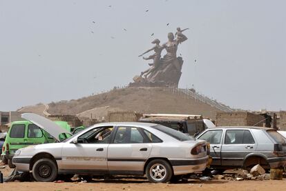 Un taller de reparación de automóviles, ante el Monumento al Renacimiento Africano, en Dakar.