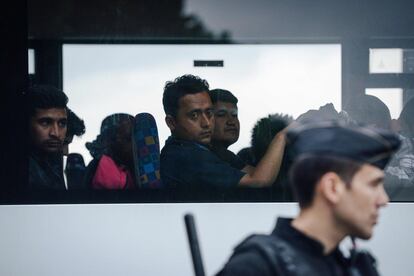 Un policía antidisturbios monta guardia junto a un autobús con migrantes tras ser desalojados de un campamento improvisado en junto al canal de Sain Martin en Quai de Valmy en París (Francia), el 4 de junio de 2018.