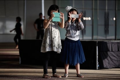 Niñas juegan con sus teléfonos en Bangkok (Tailandia), 10 de noviembre de 2013.