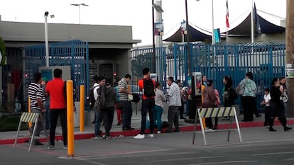 Personas en busca de empleo y trabajadores frente a una planta maquiladora en un parque industrial de Tijuana.