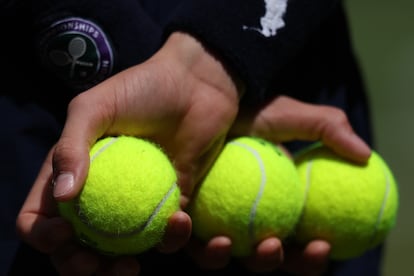Un recogepelotas retiene varias pelotas durante un partido.
