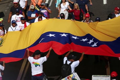 Un grupo de asistentes sostienen una bandera gigante de Venezuela durante su recorrido hacia el Palacio de Miraflores. 
