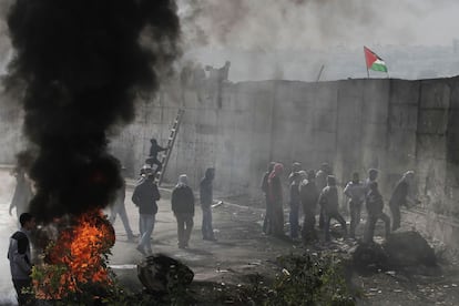 Manifestantes palestinos queman neumáticos mientras que uno de ellos trata de hacer un agujero a través del polémico muro de Israel que separa a la ciudad cisjordana de Abu Dis de Jerusalén.