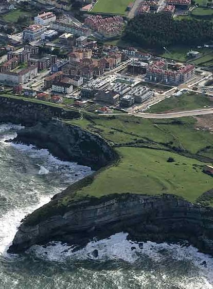 A la derecha, primeras construcciones de la macrourbanización La Talá, casi a pie de acantilado, en el municipio de Llanes, donde se van a construir hasta 500 nuevas viviendas: desde chalés de una planta, en la zona más cercana al mar y edificios de tres alturas en la parte más alejada.