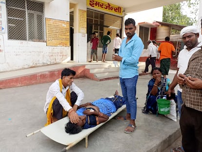 Relatives attend to a patient lying on a stretcher in the premises of a hospital in Ballia district, in northern Uttar Pradesh state, India, Sunday, June 18, 2023.