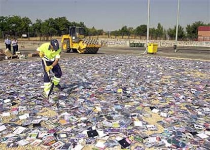 Un operario extiende discos <i>piratas</i> antes de que sean destruidos por una apisonadora.