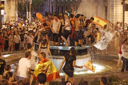 Decenas de jóvenes celebran a medianoche la victoria de la selección española en la fuente de la Puerta del Sol.