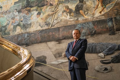 Arturo Zaldívar posa para una fotografía en el mural 'Siete crímenes mayores', del artista Rafael Cauduro.