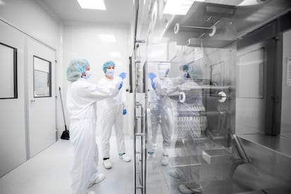 Durante la fabricación de medicamentos, la IA mejora el diseño y control de procesos. En la foto, dos mujeres con ropa de trabajo de seguridad en un laboratorio farmacéutico.