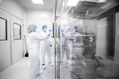 Dos mujeres con ropa de trabajo de seguridad vistas en un laboratorio farmacéutico.