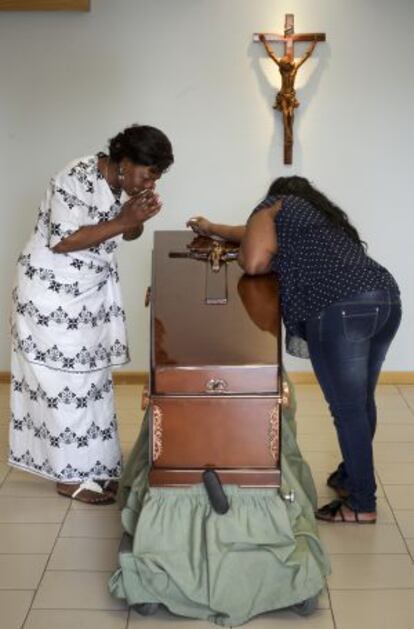 The mother of Samba, Clementine Nijba (l), weeps next to the coffin of her daughter.