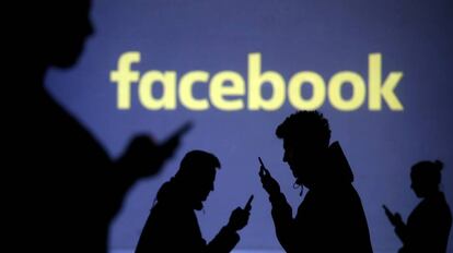 Siluetas de usuarios de móvil frente al logo de Facebook