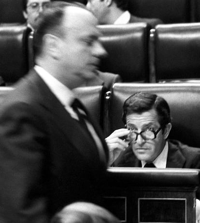 Manuel Fraga pasa ante Adolfo Su&aacute;rez, sentado en su esca&ntilde;o, que le mira por encima de sus gafas durante una sesi&oacute;n de Congreso de los Diputados en 1979.