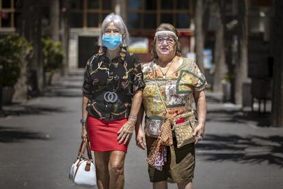 Dos vecinas de Benidorm pasean protegidas contra el coronavirus. El silencio se apodera de una ciudad conocida por su incesante actividad.