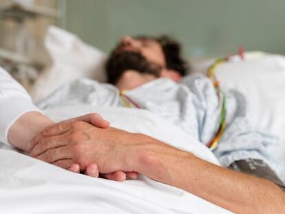 Personal médico sostiene la mano de un paciente.